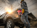 Outdoor jobsite. Man wearing hardhat stands next to pickup truck with open tailgate